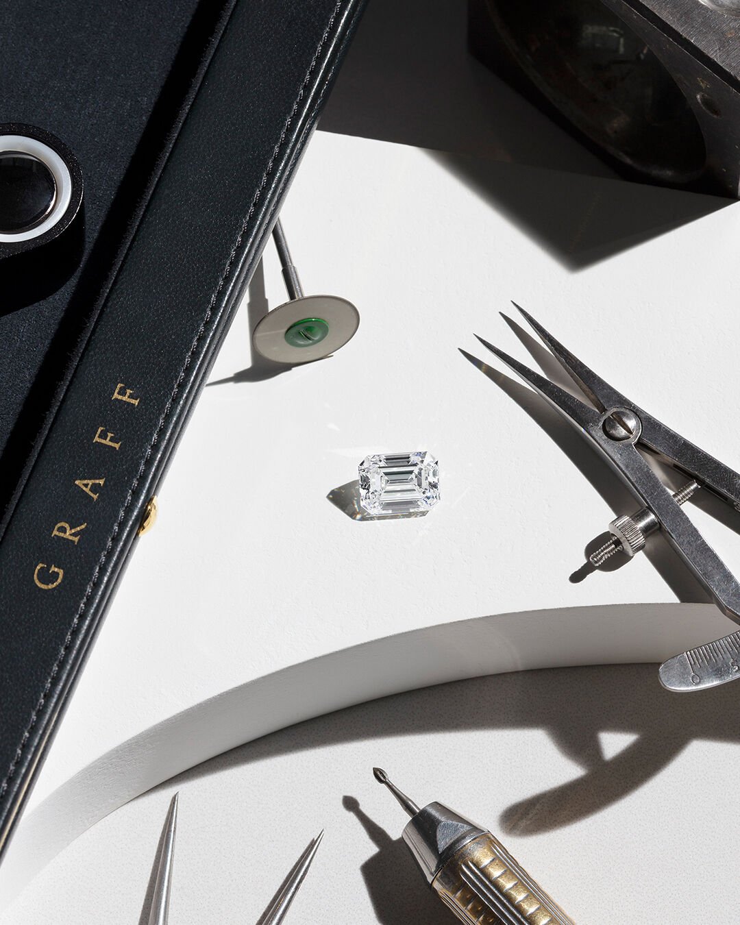 Image shows loose Graff Emerald Cut diamond and Graff workshop tools