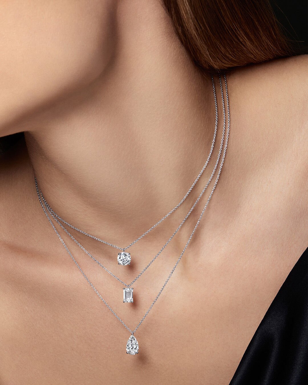 Image shows model wearing Classic Graff Round, Emerald Cut and Pear Shape diamond pendants