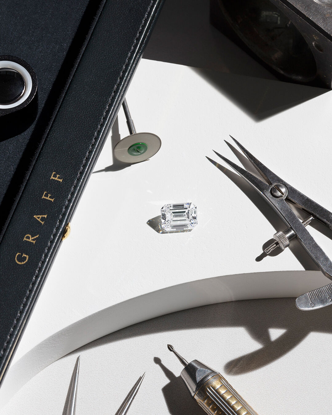 Image shows loose Graff Emerald Cut diamond and Graff workshop tools