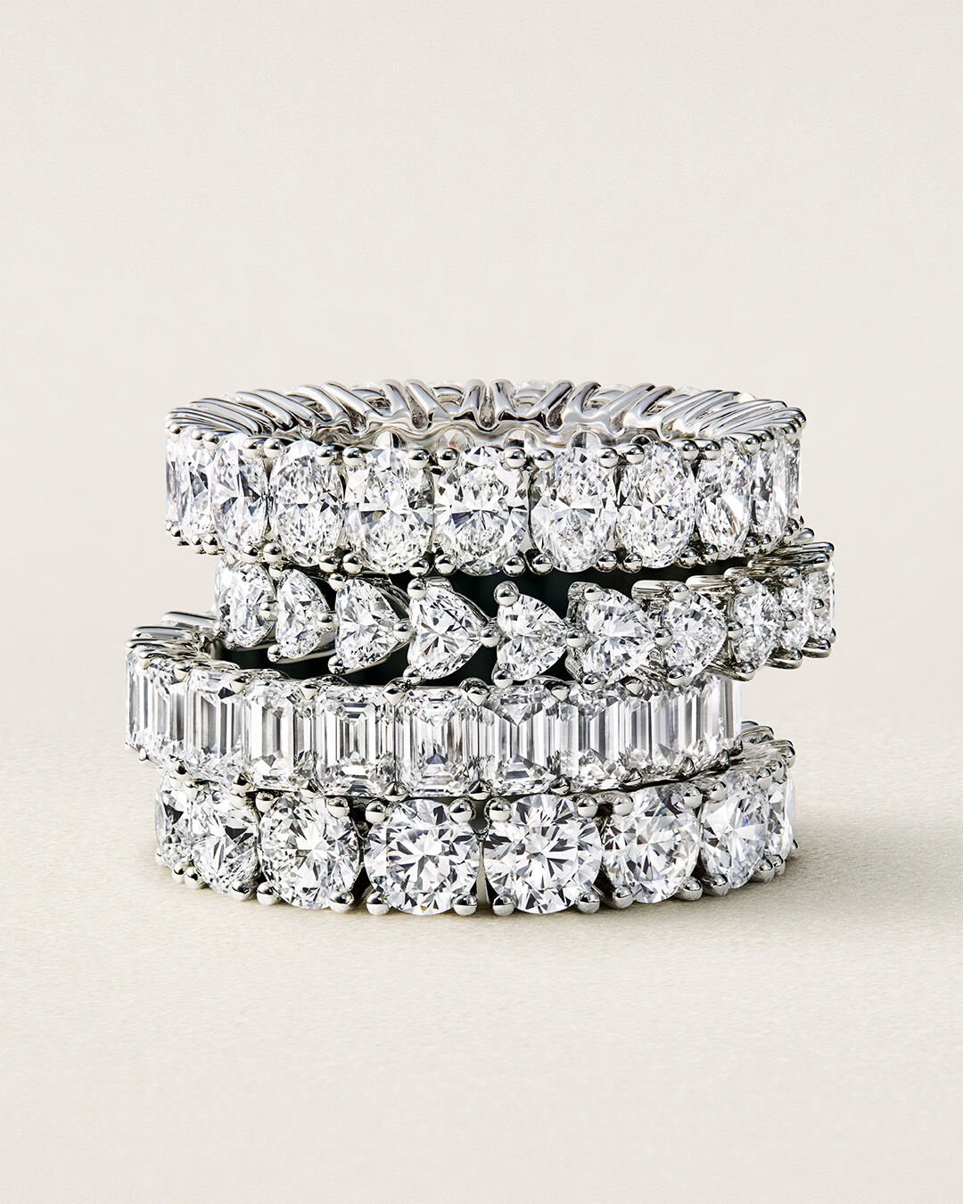 Image shows model hand wearing Graff Emerald Cut Promise diamond engagement ring and Emerald Cut diamond eternity ring